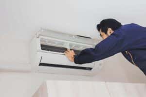 man in blue overalls servicing a heat pump